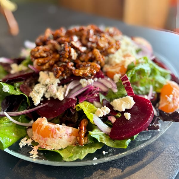A vibrant salad with candied walnuts, beets, red onion, mandarin oranges, and feta cheese.